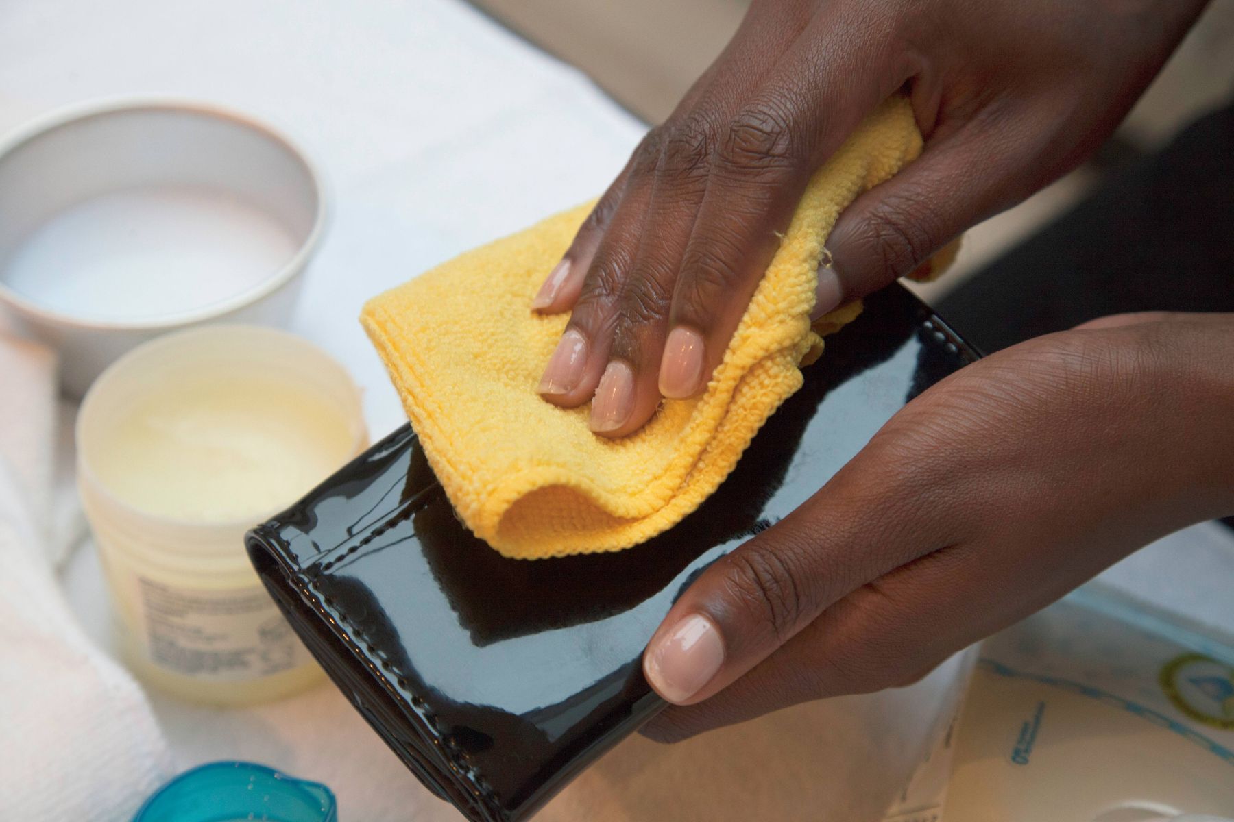 Men carefully washing a patent leather wallet with precision and care.